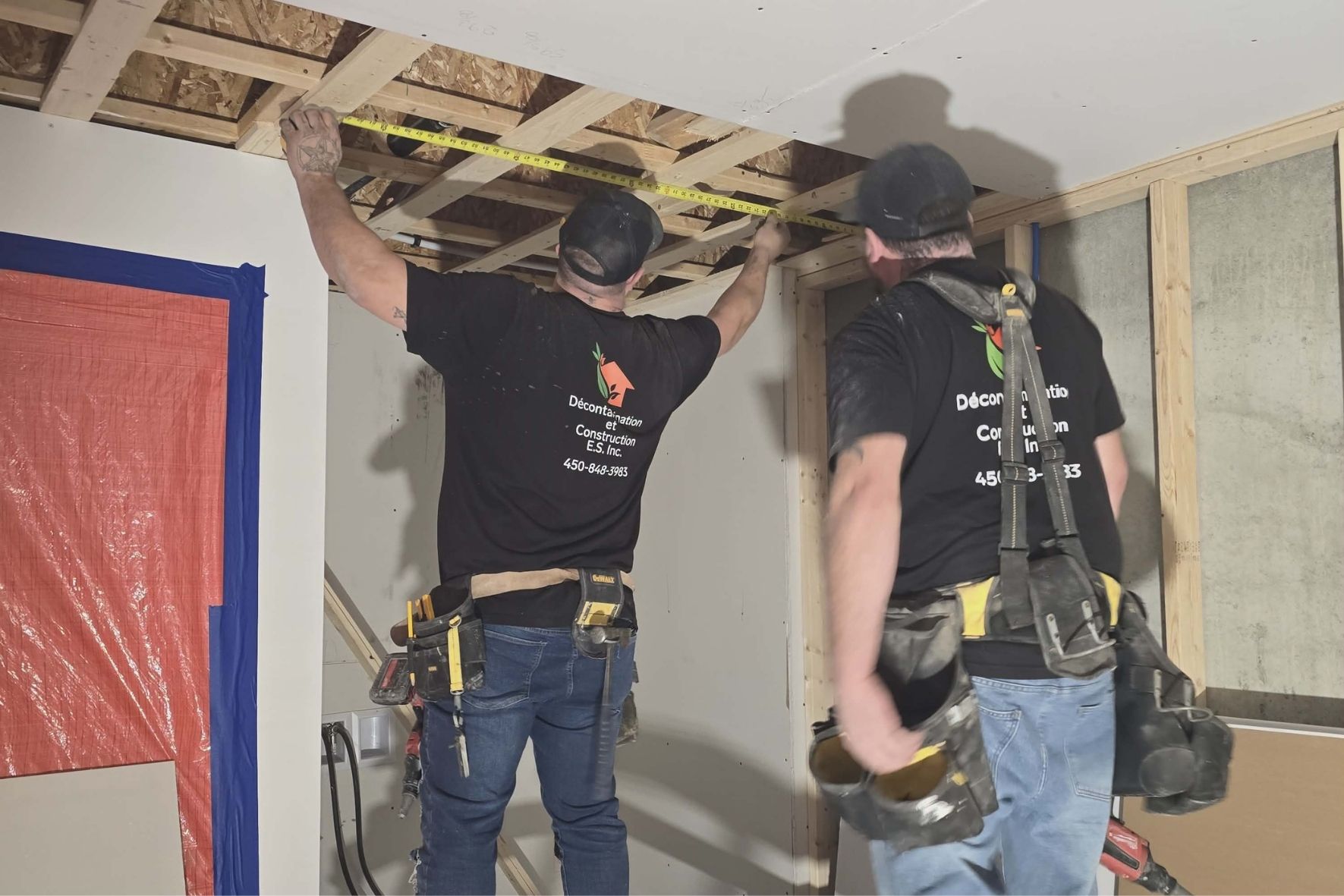 Deux travailleurs mesurant une structure intérieure en bois dans un espace rénové  sur la Rive-Sud de Montréal 